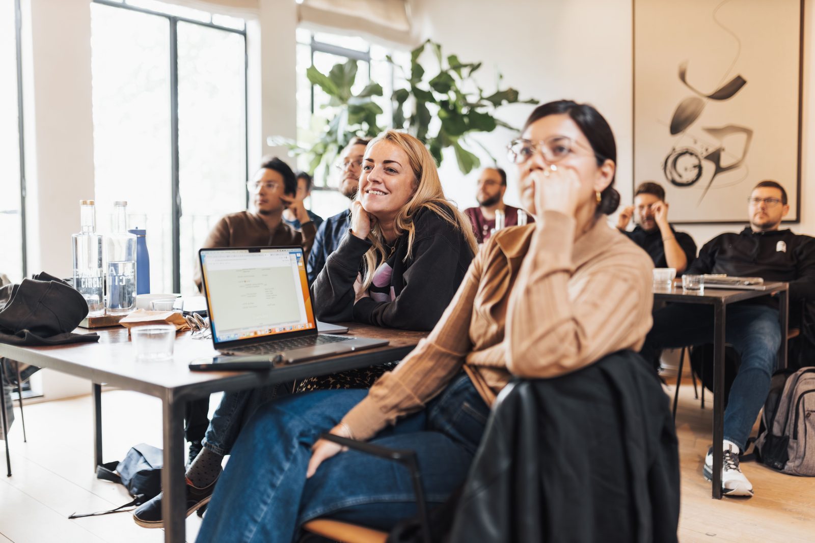 Teilnehmerinnen verfolgen aufmerksam ein Seminar, vorne ein aufgeklappter Laptop